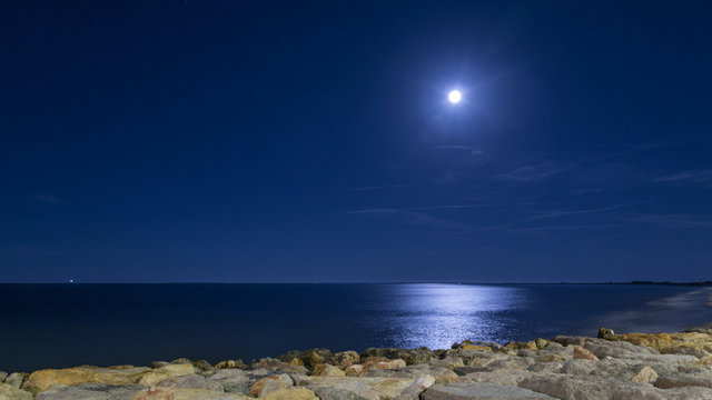 The moon in the sky and lune pathe in the sea. Night. Catalonia, L'Ampolla, Spain