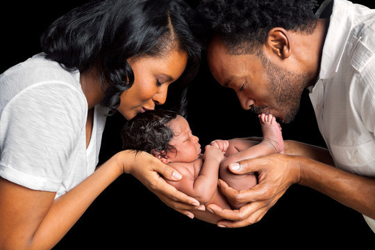 African American Couple Cradles Newborn Daughter Between Them In