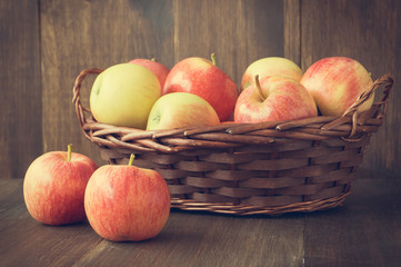 Apples in basket on wooden rustic background
