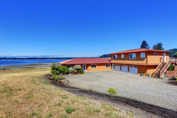 Fototapeta na wymiar American waterfront house, orange exterior paint and three garage spaces