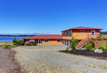 Fototapeta na wymiar American waterfront house, orange exterior paint and three garage spaces