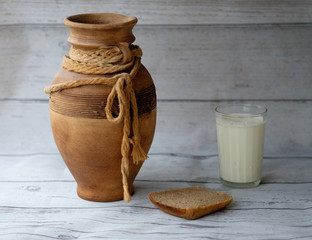 Глиняный кувшин, стакан молока и горбушка хлеба 