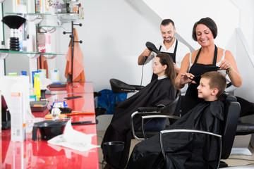 Kid in elementary school age getting hairdo by female