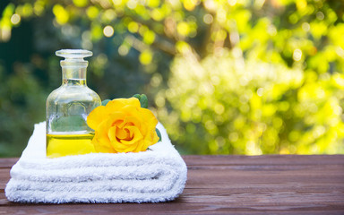 Essential rose oil and towel. Fragrant yellow rose. Aromatherapy and massage. The magic elixir for...