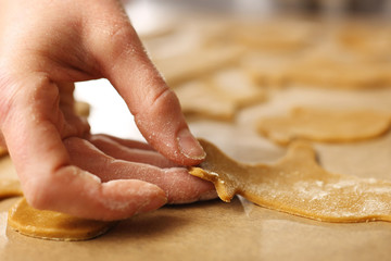 Kobieta układa na pergaminie wykrojone ciasteczka