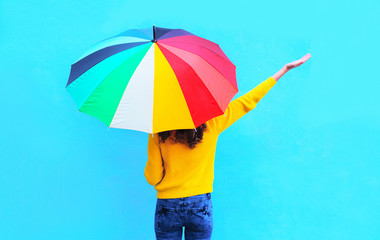 Happy young woman with colorful umbrella raised hands up enjoyin