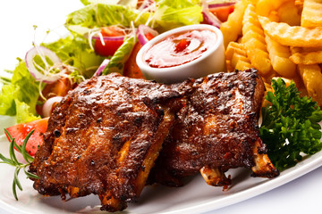 Grilled ribs, French fries and vegetables on white background
