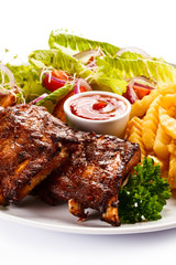 Grilled ribs, French fries and vegetables on white background