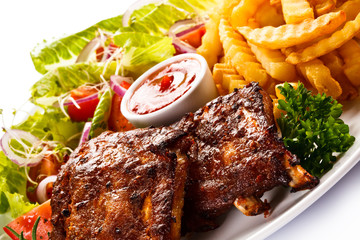 Grilled ribs, French fries and vegetables on white background