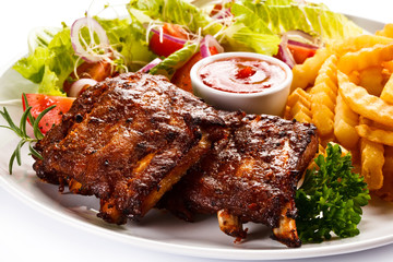 Grilled ribs, French fries and vegetables on white background