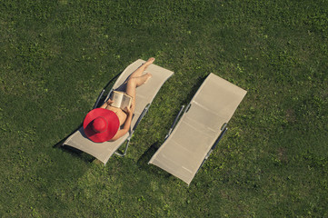 woman lying on sunbad with book
