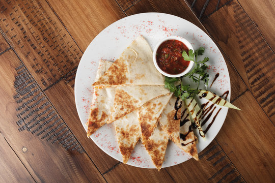 quesadilla with beef and chicken on brown wood table. quesadilla and sauce.