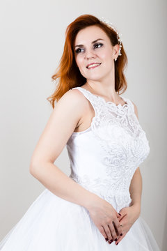 red-haired bride in a wedding dress, bright unusual appearance. Beautiful hairstyle and professional make-up