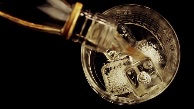 barman pouring whiskey with ice cubes in the glass on wood table, view top, time of relax with whisky