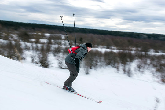 Skier hiker goes downhill in forest virgin snow. Motion blurred image.