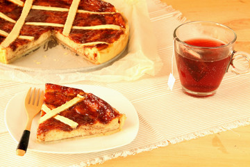 Homemade crostata cake with jam and ricotta cheese and a cup of red infusion.
