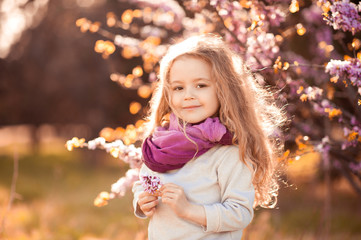 Smiling kid girl 4-5 year old holding flower wearing casual clothes outdoors. Looking at camera. Childhood.