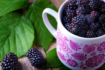 Cup of fresh natural blackberries with leafs
