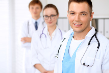 Fototapeta premium Cheerful smiling male doctor with medical staff at the hospital