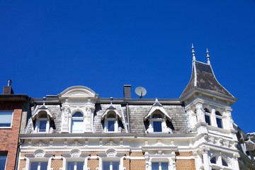 Obraz premium Historic Renaissance Revival architecture in the Frankenberger Quarter, Aachen, Germany with a townhouse with ornate stone carving, dormer windows and turret against a blue sky