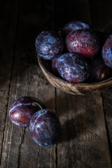 Zwetschgen in einer Holzschale auf einem alten Holzuntergrund