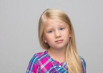 Portrait of a charming blonde little girl, isolated on gray background