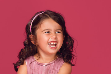 Happy energetic little girl on red pointing fresh. Candid portrait of cheering beautiful young white Caucasian woman on red background.