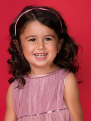 Happy energetic little girl on red pointing fresh. Candid portrait of cheering beautiful young white Caucasian woman on red background.