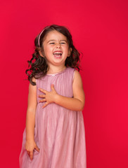 Happy energetic little girl on red pointing fresh. Candid portrait of cheering beautiful young white Caucasian woman on red background.