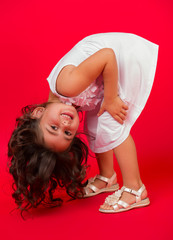 Happy energetic little girl on red pointing fresh. Candid portrait of cheering beautiful young white Caucasian woman on red background.