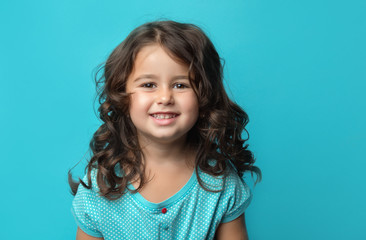 portrait of a happy, positive, smiling, little girl, cyan background © Alezhano