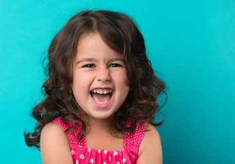 portrait of a happy, positive, smiling, little girl, cyan background