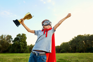 Superhero boy with a championship trophy in hands on nature show © Studio Romantic