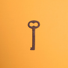 Old rusted key on yellow ocher background - Top view