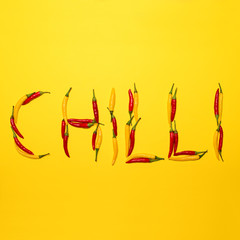 Red hot chili peppers on yellow background making word " CHILLI"