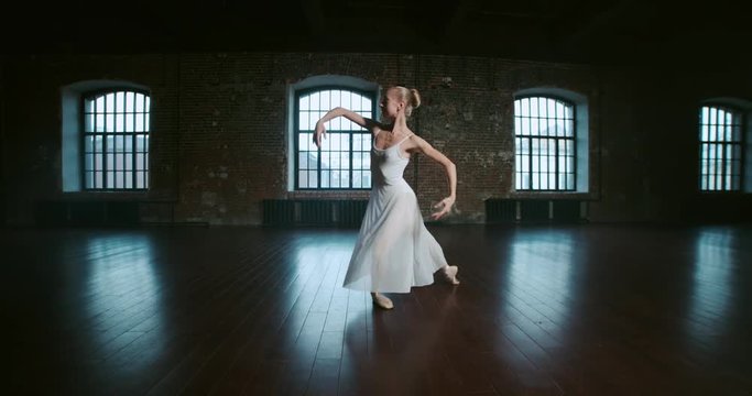 beautiful ballerina in white dress performs the elements of dance in the loft Studio, slow motion