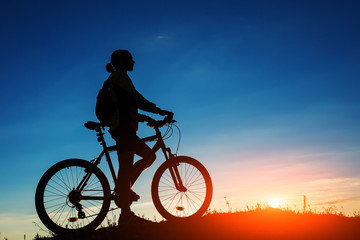 Fototapeta na wymiar Silhouette of cyclist and a bike on sky background