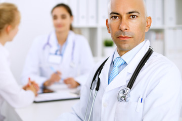 Fototapeta premium Confident bald doctor man with medical staff at the hospital