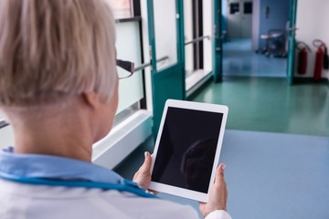 Doctor using digital tablet in corridor