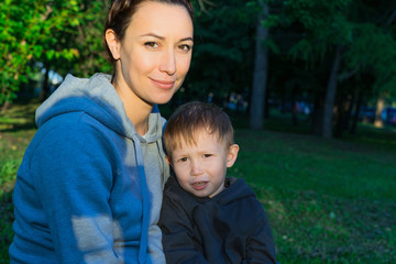Mother with son sitting on the grass in the park.