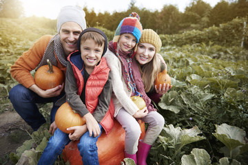 Happy family in the field full of pumpkin