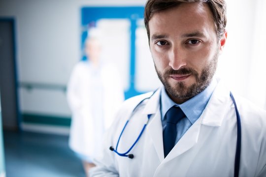Confident doctor standing in hospital corridor