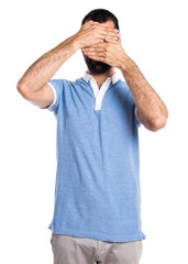 Man with blue shirt covering his face