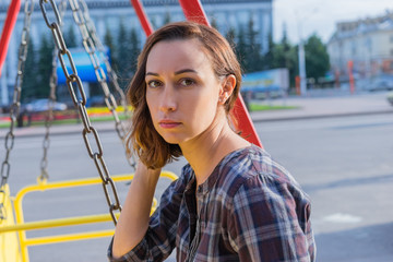 Young girl sitting on a swing in the city