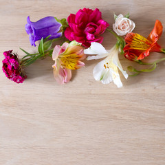 Creative arrangement made of different flowers on wooden background with space for text.