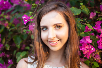portrait of young beautiful woman girl on background of bougainvillea purple violet flowers in blossom