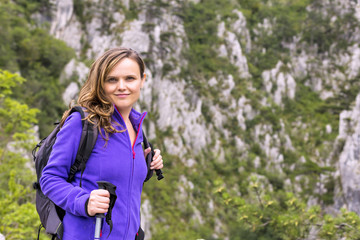 Young  beautiful woman holding hiking pole while climbing the ro