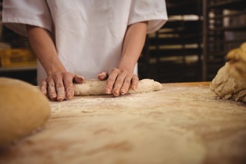 Mid-section of female baker kneading a dough