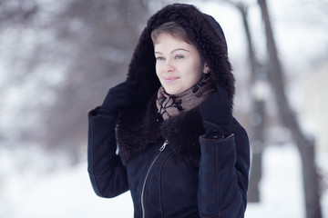 Winter woman in a fur coat on the snow outside