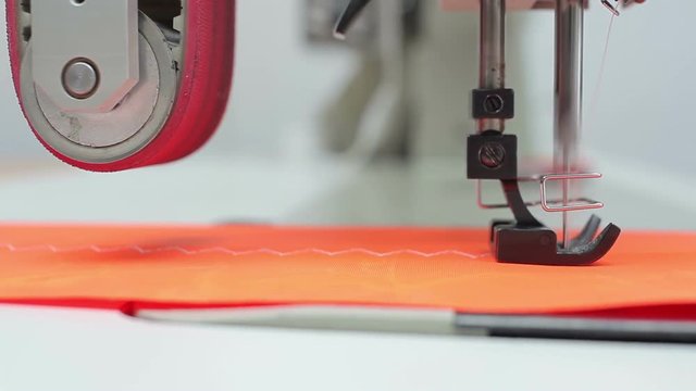 Needle of sewing machine moves through the cloth